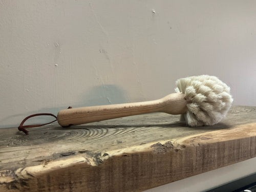 Image of beech wood dish brush with leather strap in a wooden table